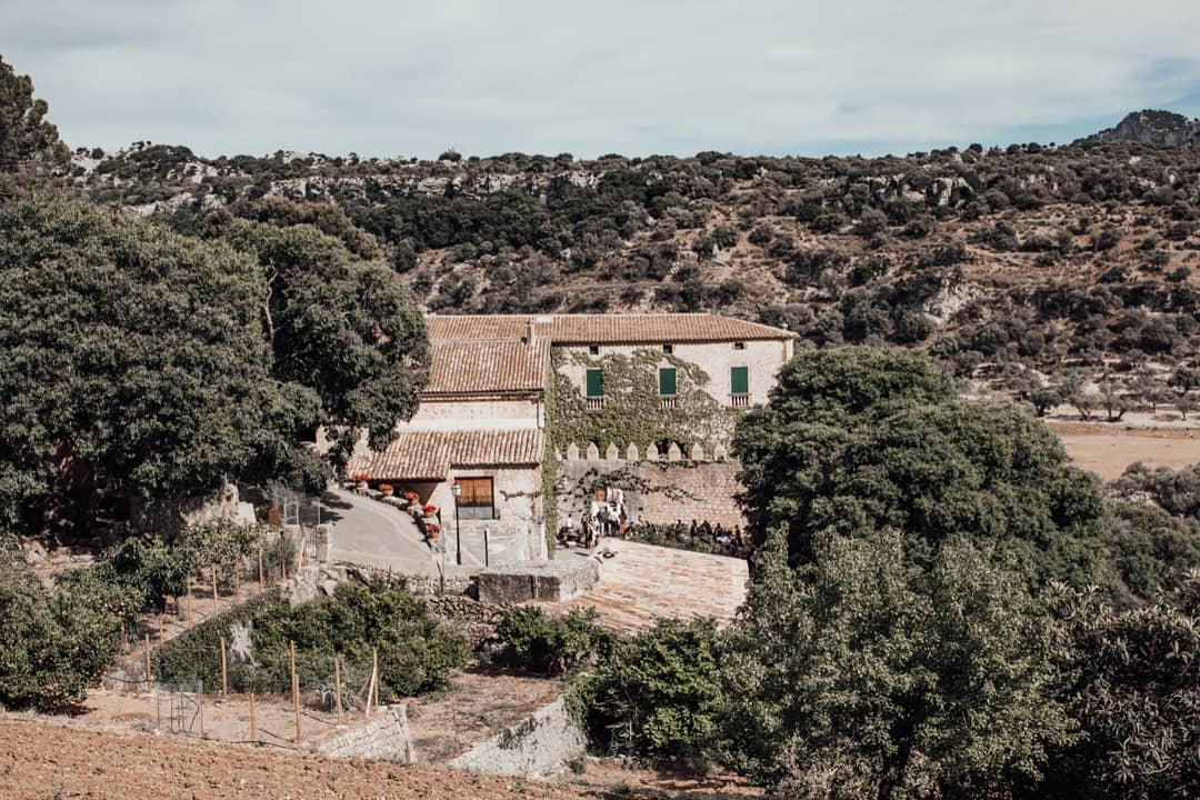 Vista aérea de Finca Comasema en Mallorca, rodeada de exuberante vegetación y majestuosas montañas