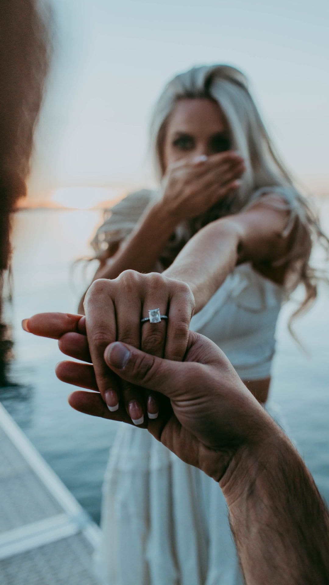 Pedida de mano en la playa al atardecer con un anillo de compromiso.