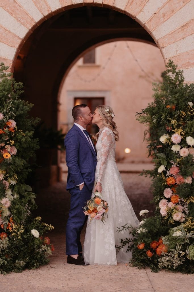 Erin and Charlie under a flower-framed stone arch at Finca Morneta