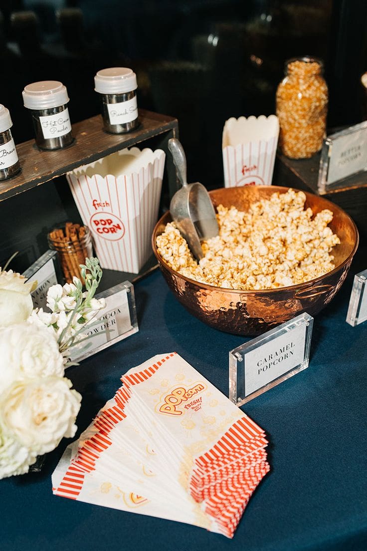 Mesa con palomitas de caramelo y condimentos, una idea divertida para la recena de boda.