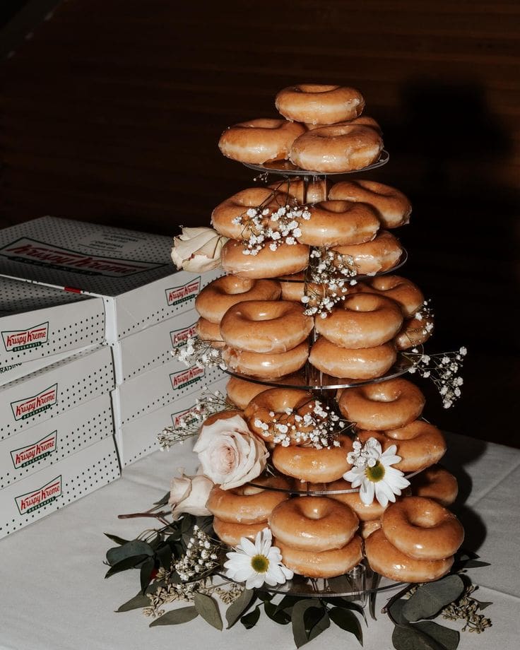 Torre de donuts glaseados decorada con flores, ideal para una recena de boda original.
