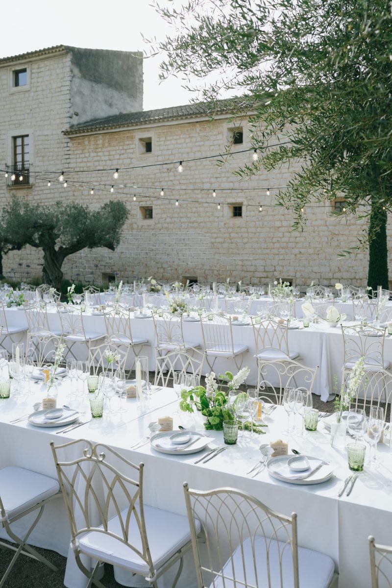Long tables beside the olive trees and the stone facade of Finca Morneta, at Sophie and Rory's wedding