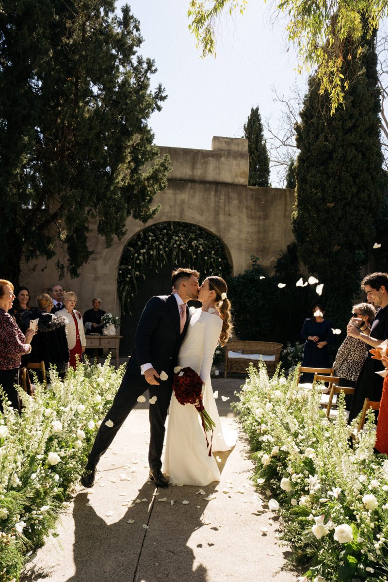 Ana and Rafa kiss in a shower of petals as they leave their ceremony at Mas de Alzedo, Valencia