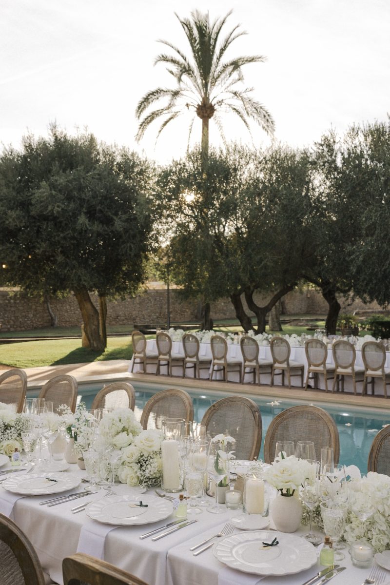 Mesa larga junto a la piscina de la Finca Morneta, toda en blanco, en la boda de Emily y Franky