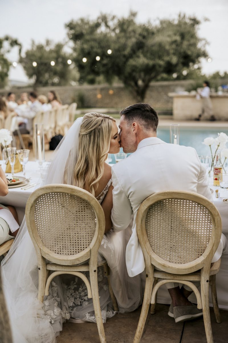 Melissa and Niclas kiss at the table beside the pool at Finca Morneta, Mallorca