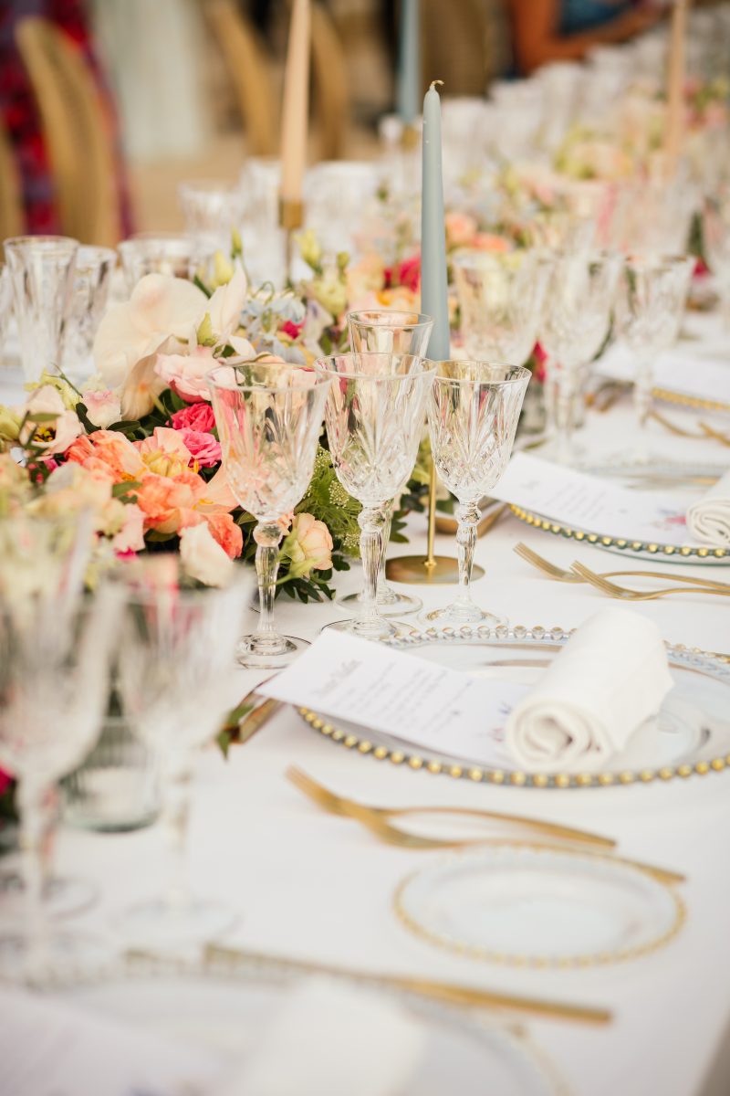 Place setting with cut crystal, gold and coral flowers, at Stephanie and Mau's wedding