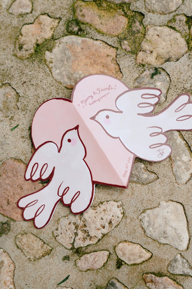 Programa de la ceremonia con forma de dos palomas sobre el suelo de piedra