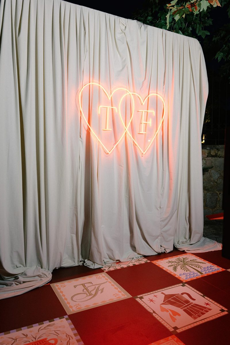Corazón de neón con las iniciales T y F sobre una pista de baldosas pintadas